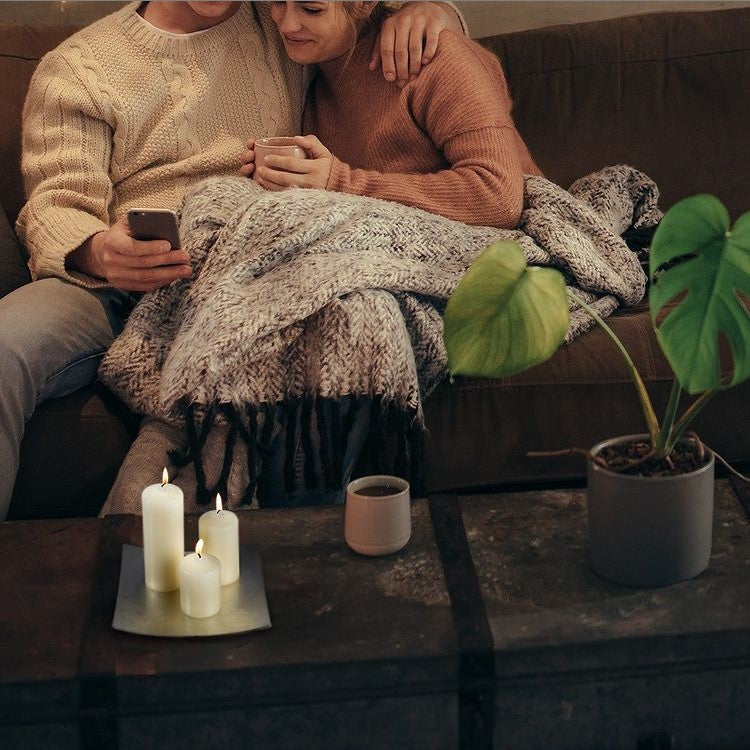 3 lit candles with a couple snuggled on the sofa together