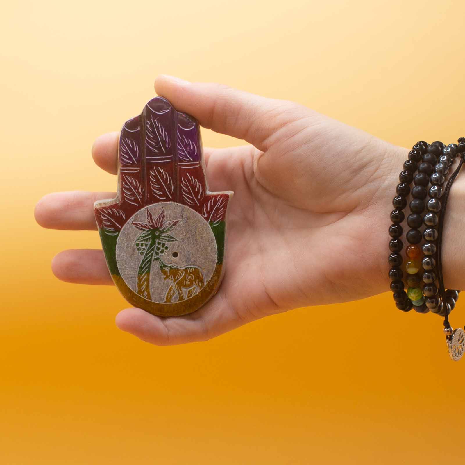 Image: Soapstone Hamsa Incense Holder featuring Elephant & Palm design, perfect for incense, meditation, and gifts. Shown in a hand from little finger to thumb