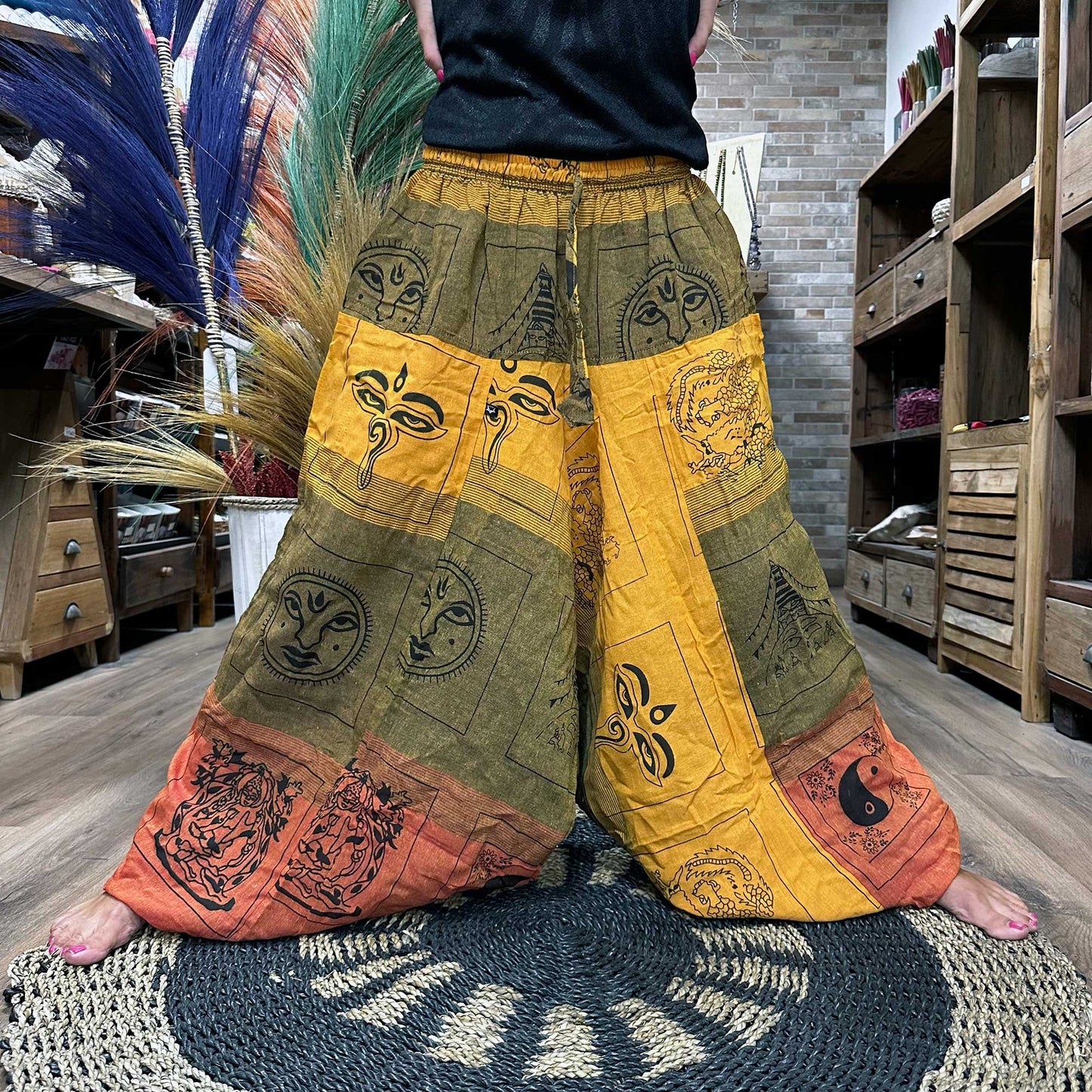 Someone standing in a wide stance wearing the Aladdin Yoga & Festival Pants, himalayan print on orange