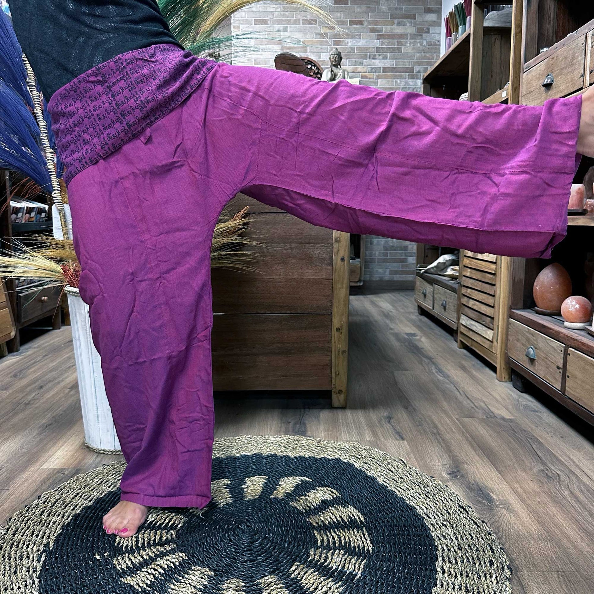 Person standing on one leg wearing unisex Thai Fisherman yoga pants, mandala mantra on purple