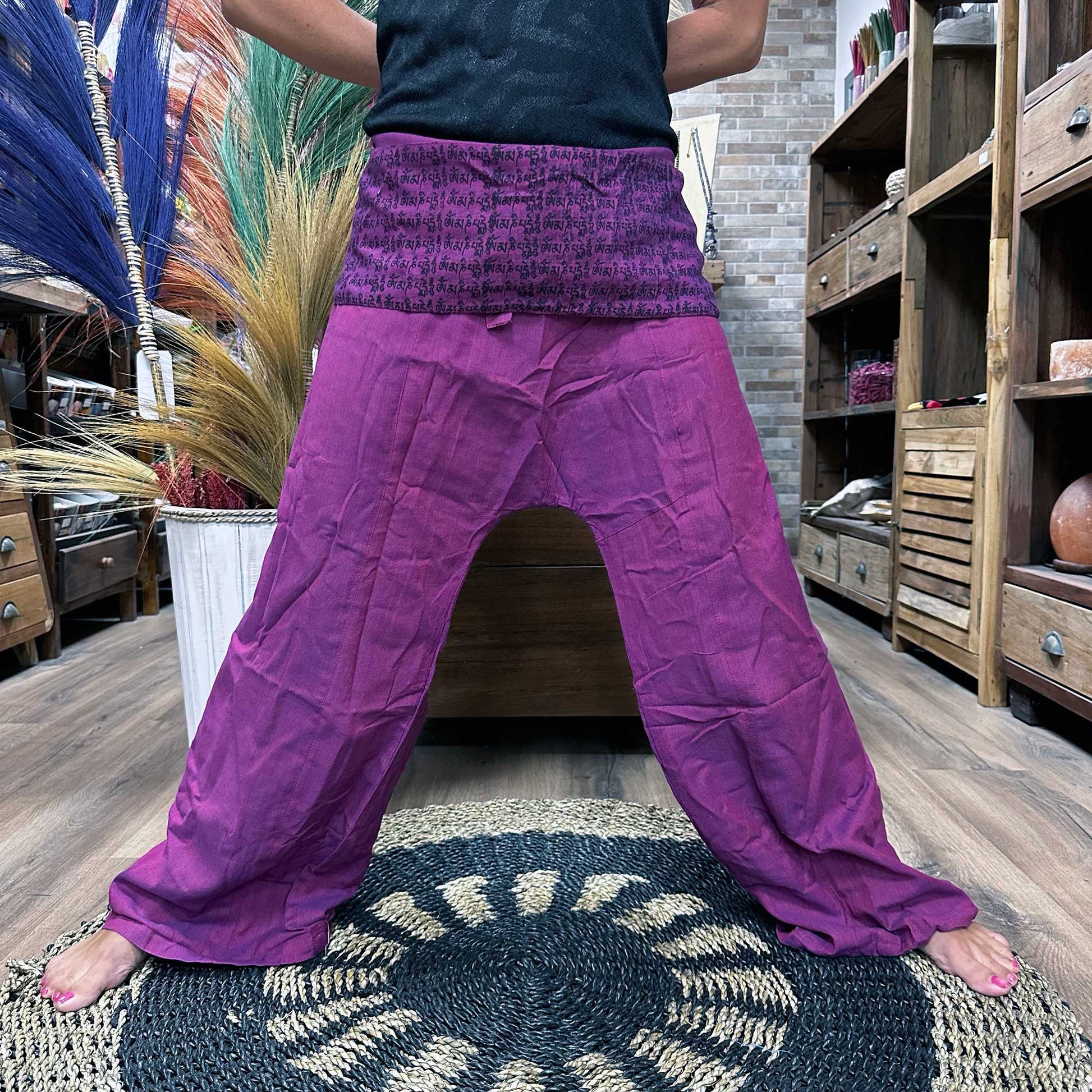 Person with a wide stance wearing unisex Thai Fisherman yoga pants, mandala mantra on purple