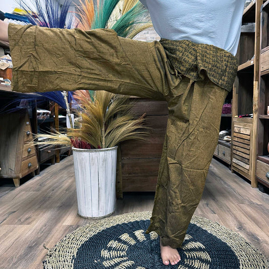 Person standing on one leg wearing unisex Thai Fisherman yoga pants made from 100% cotton, mandala mantra on orange