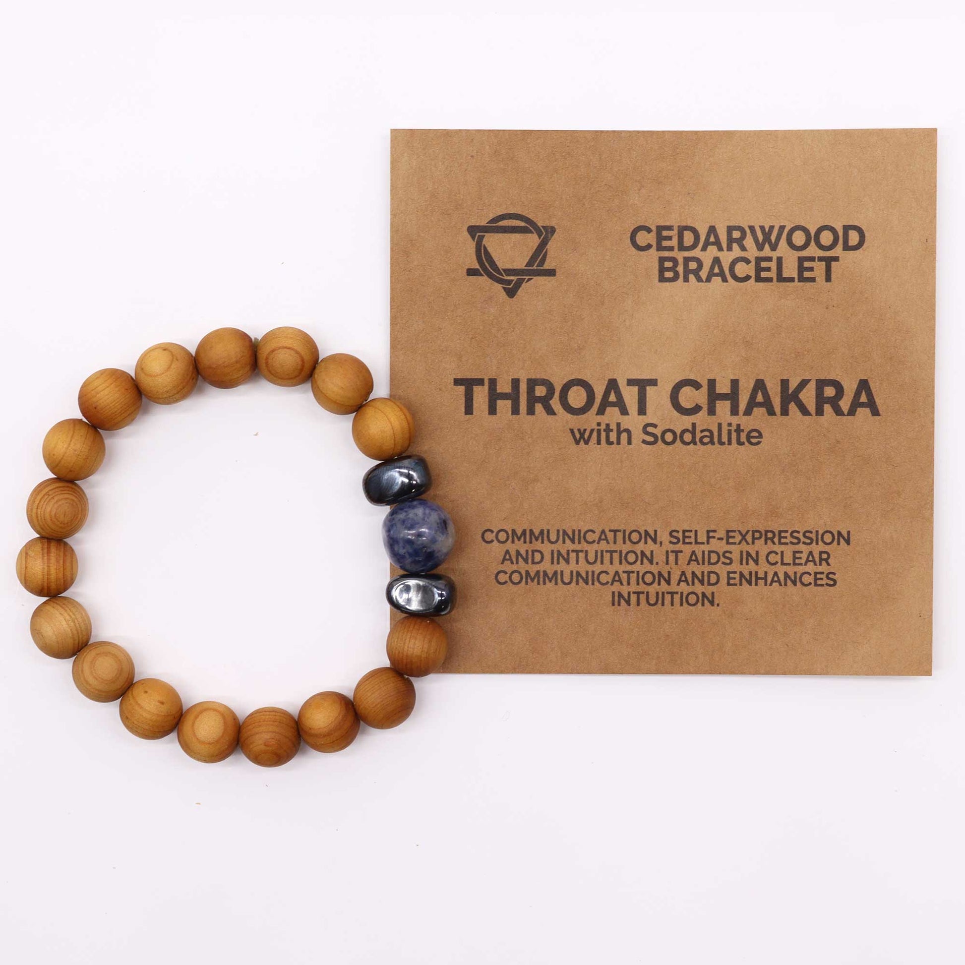 Handcrafted cedarwood throat chakra bangle with Sodalite gemstones. Eco-friendly unisex jewelry for spiritual balance. Shop now! Image of bracelet on white background next to packaging