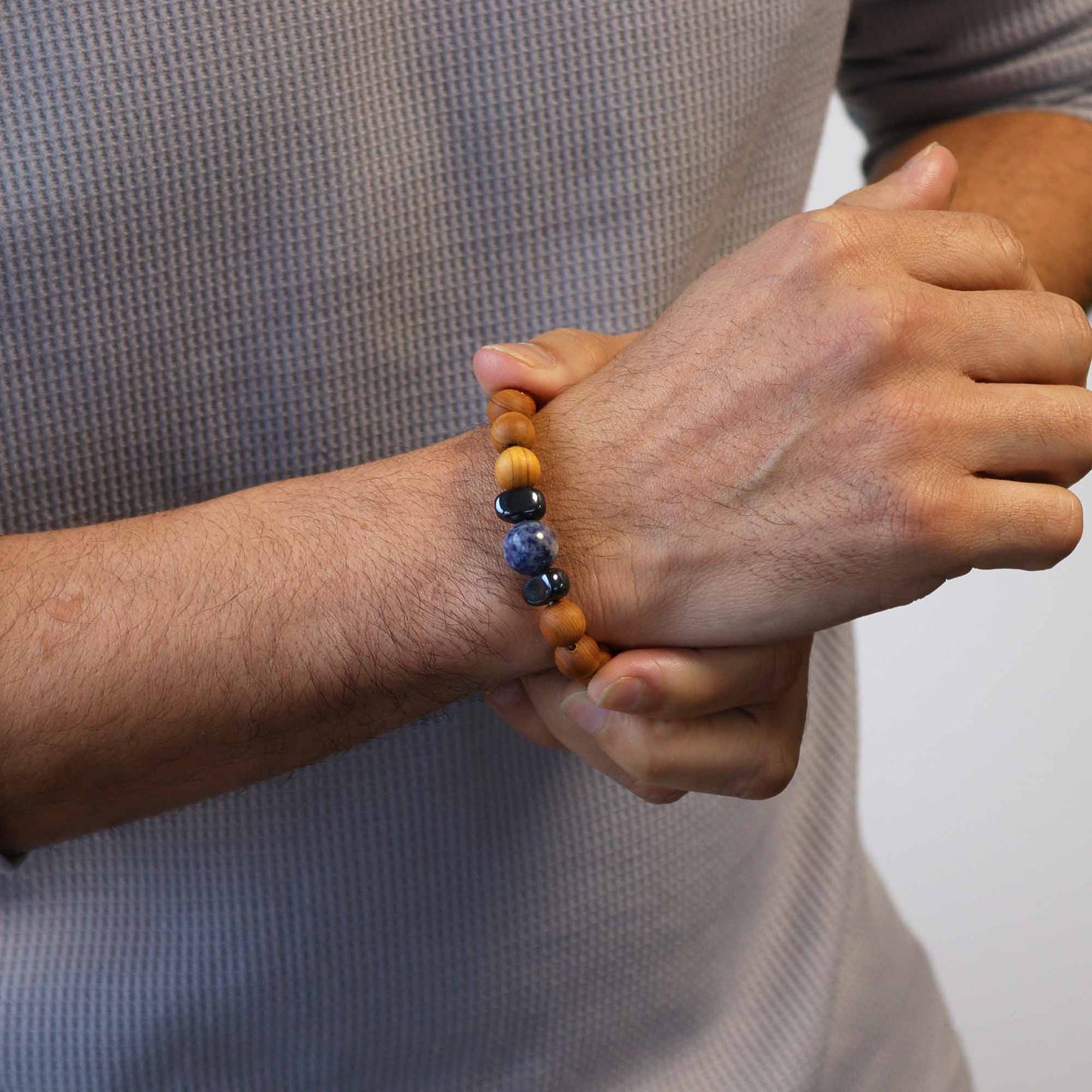 Handcrafted cedarwood throat chakra bangle with Sodalite gemstones. Eco-friendly unisex jewelry for spiritual balance. Shop now! Image of bracelet on a persons right wrist.