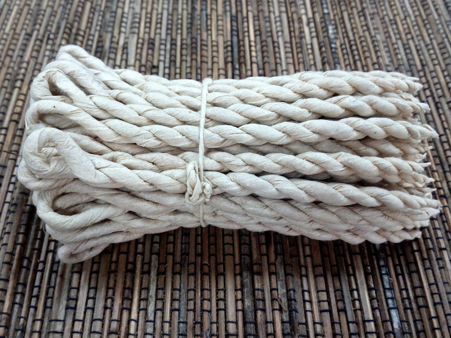 Image of a bunch of cedar rope incense on cane matting  background, hand made in nepal for relaxation home fragrance. Image shows no packaging just the rope .