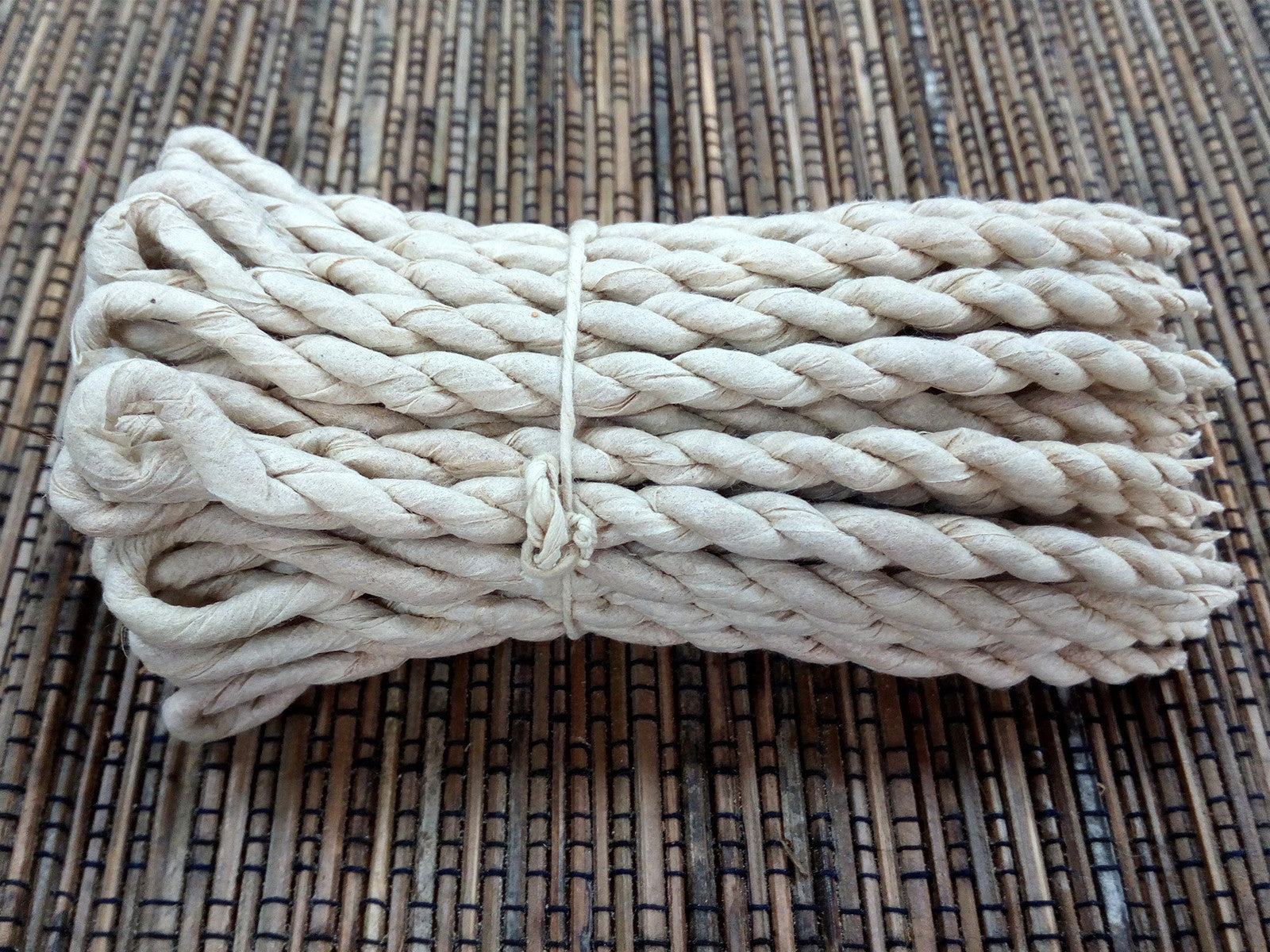 Image of a bunch of cedar rope incense on cane matting  background, hand made in nepal for relaxation home fragrance. Image shows no packaging just the rope .