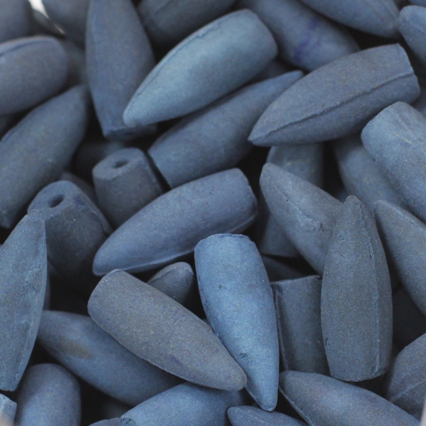 Image shows a very close up of a pile of back flow incense cones in Tibetan Musk fragrance