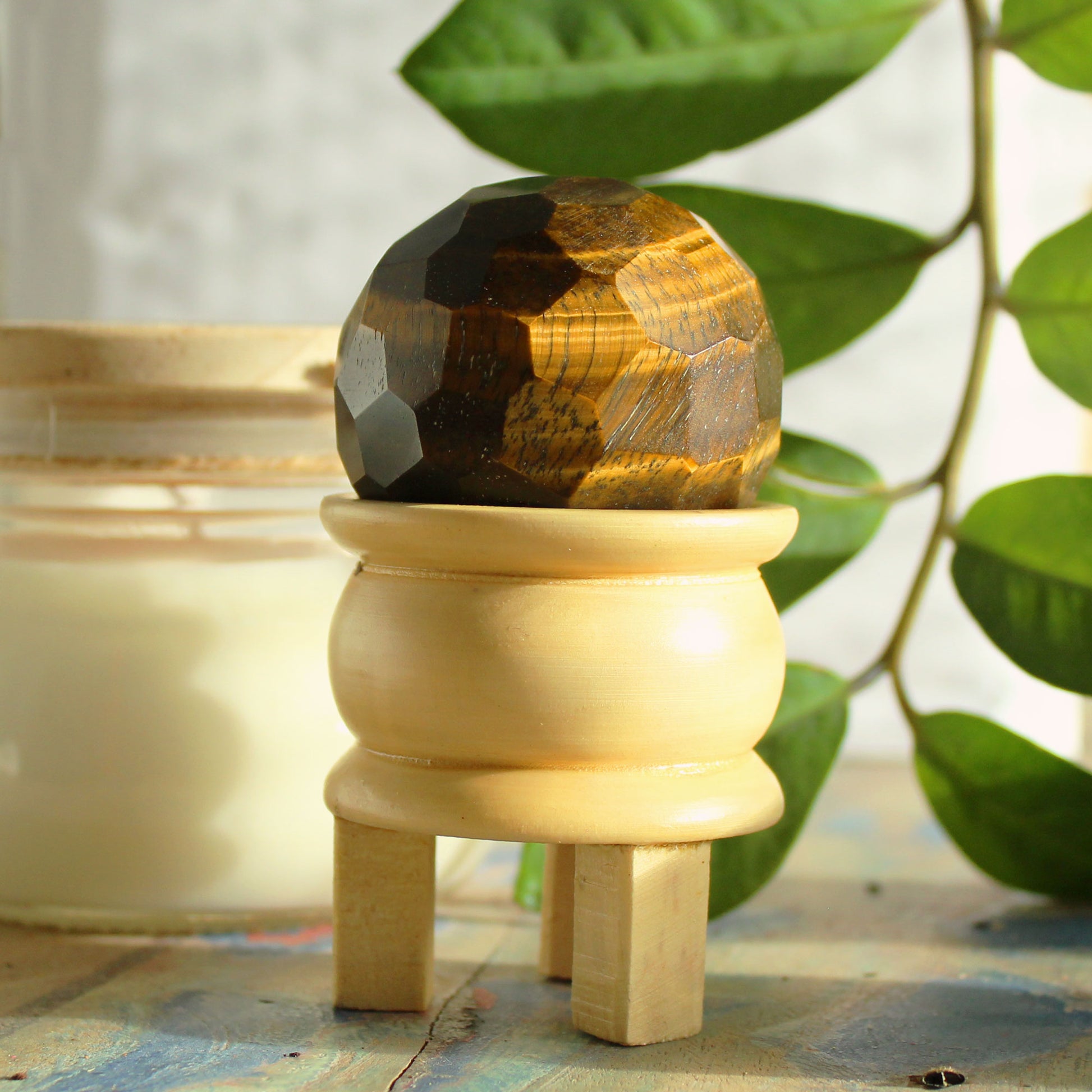 Gemstone Faceted Healing Ball & Stand - Tigereye. Image of a Tigereye Gemstone Faceted Healing Ball with wooden stand and complementary spheres, perfect for meditation and healing practices.